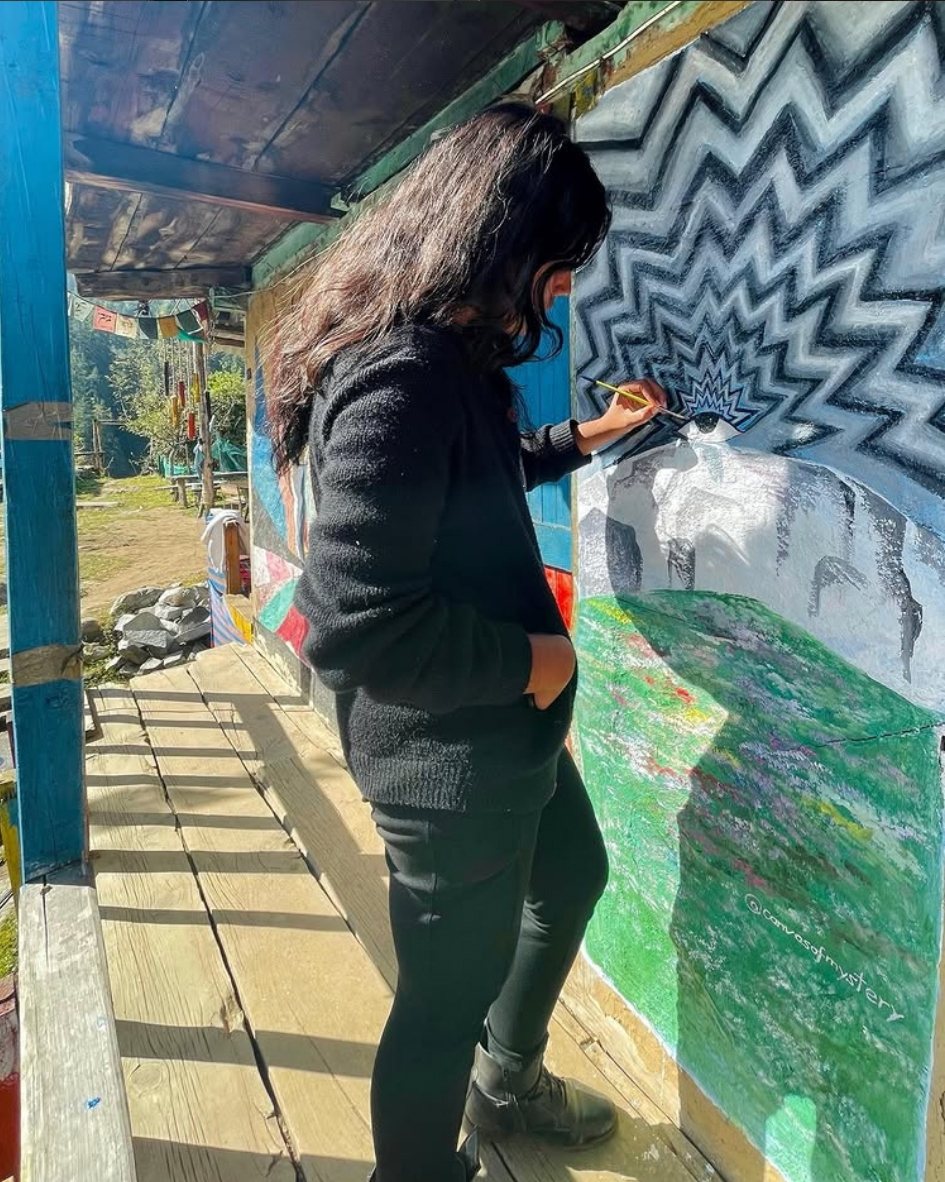 The artist painting a mural of an eye above mountains